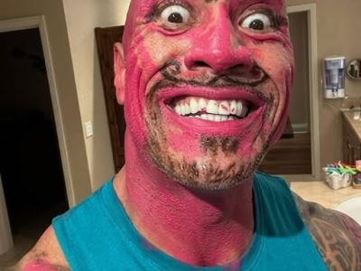 The Rock covered in pink makeup making a funny facial expression