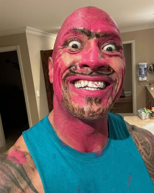 The Rock covered in pink makeup making a funny facial expression